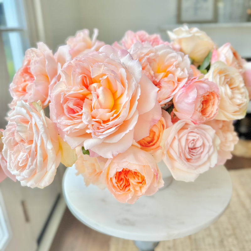 Bouquet of pink and peach roses on a marble surface with a blurred indoor background
