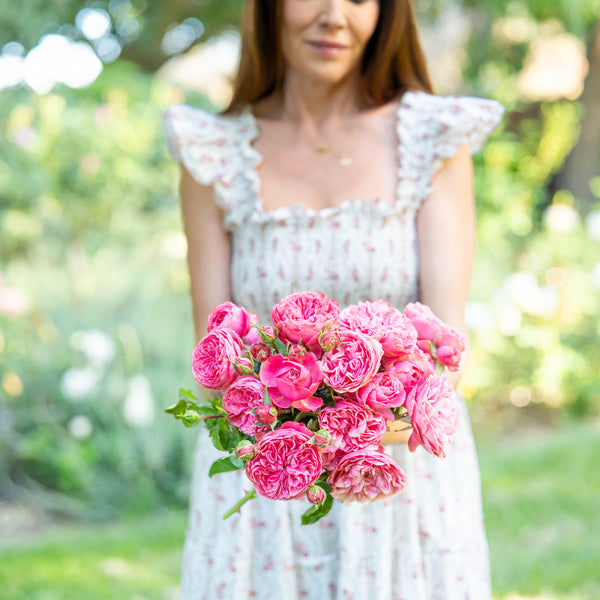 Woman holding a bouquet of pink flowers in a garden setting